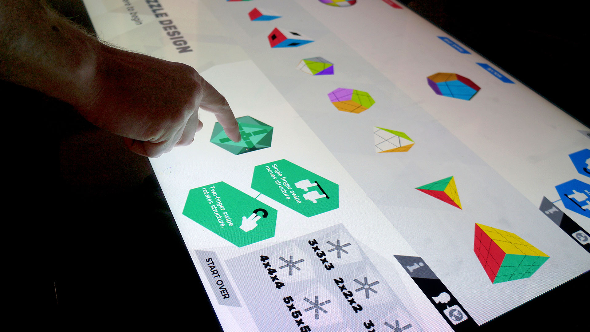 The final Twisty Puzzle interface presents color-coded user stations on a large touch table display.