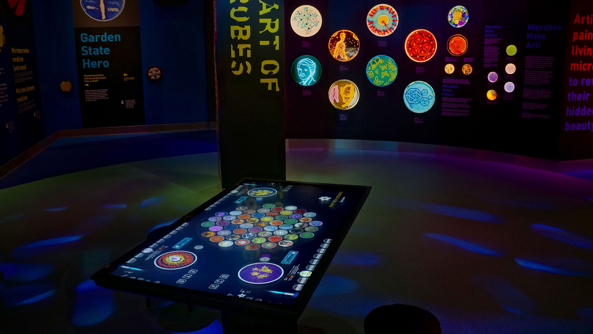 The interface design complements the illuminated microbial art samples found throughout the gallery